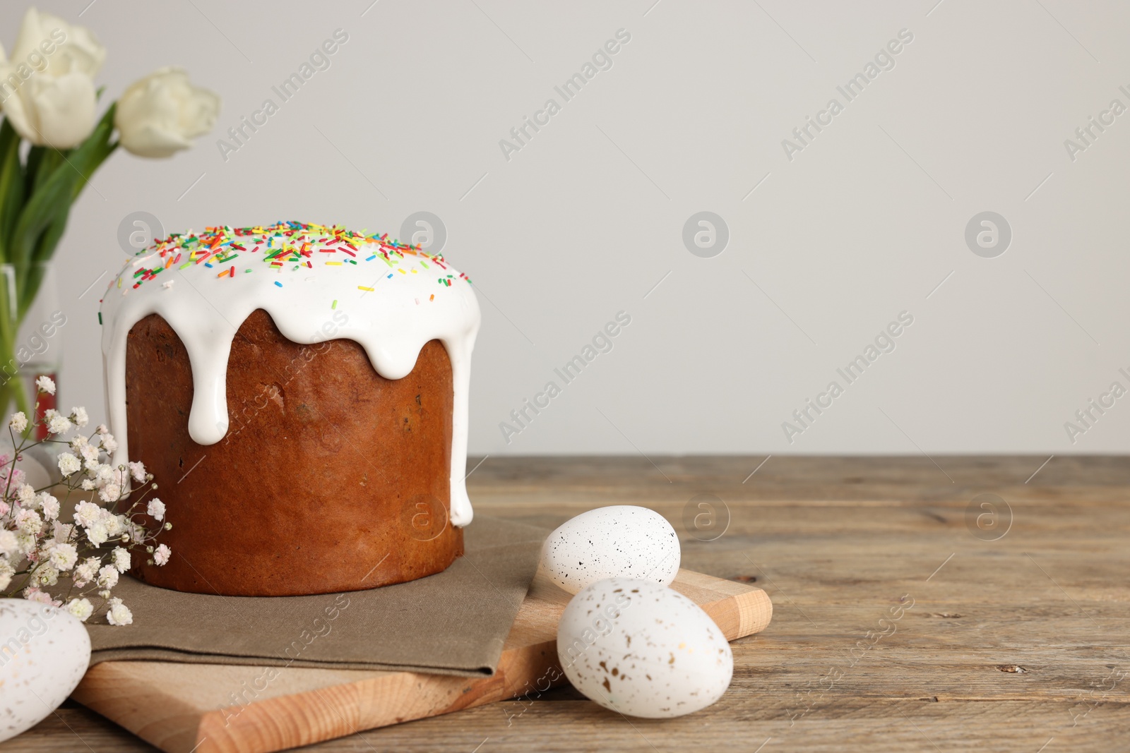 Photo of Tasty Easter cake, decorated eggs and flowers on wooden table. Space for text
