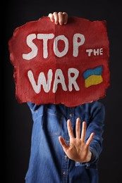 Photo of Woman holding poster with words Stop the War on black background