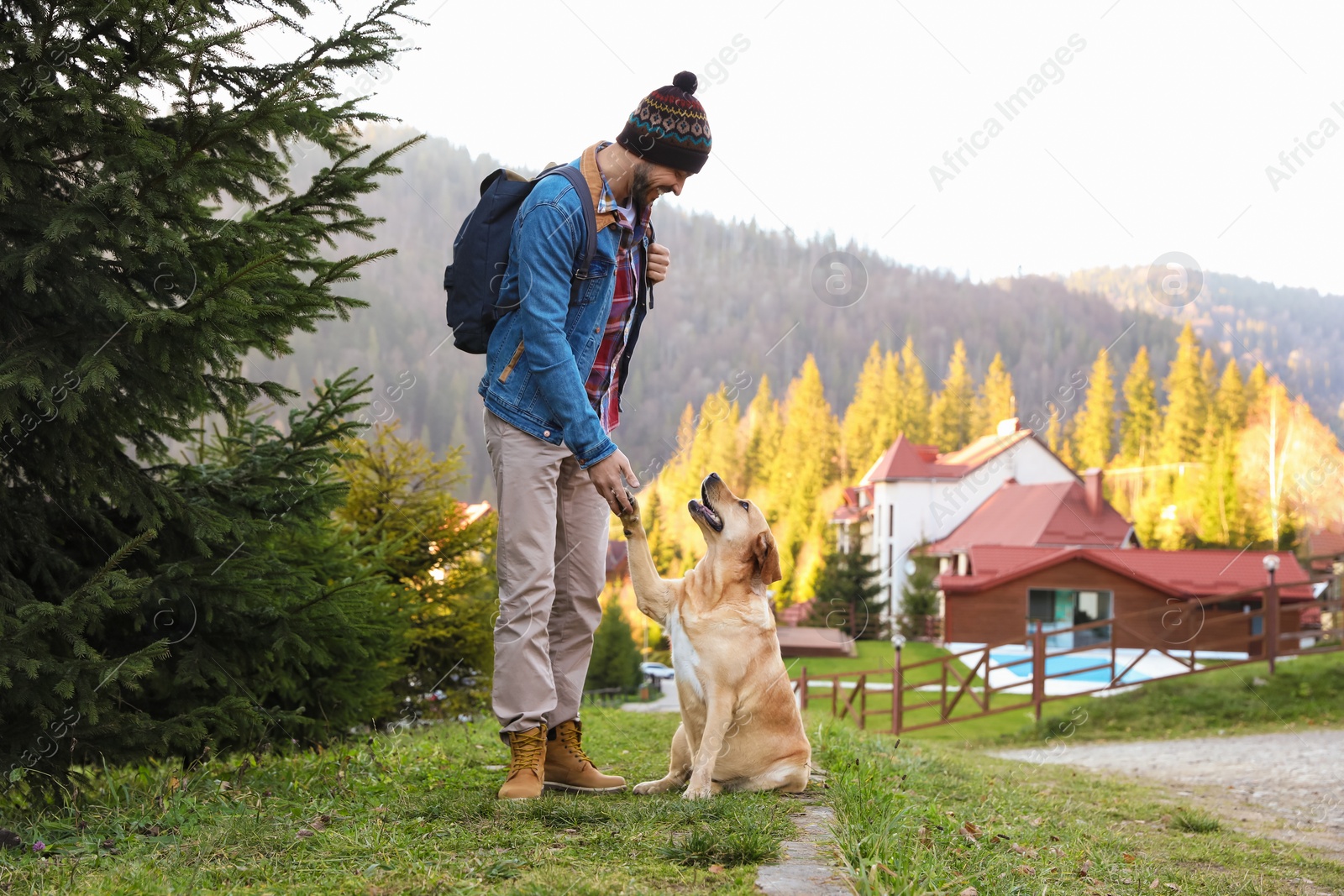 Photo of Happy man and adorable dog in mountains. Traveling with pet