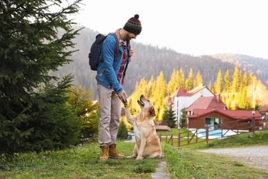 Photo of Happy man and adorable dog in mountains. Traveling with pet