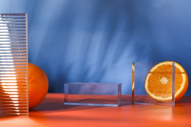 Photo of Presentation for product. Podium and tasty fresh oranges on red table against blue background, closeup. Space for text
