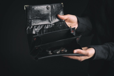 Photo of Poor woman showing her empty wallet on dark background, closeup