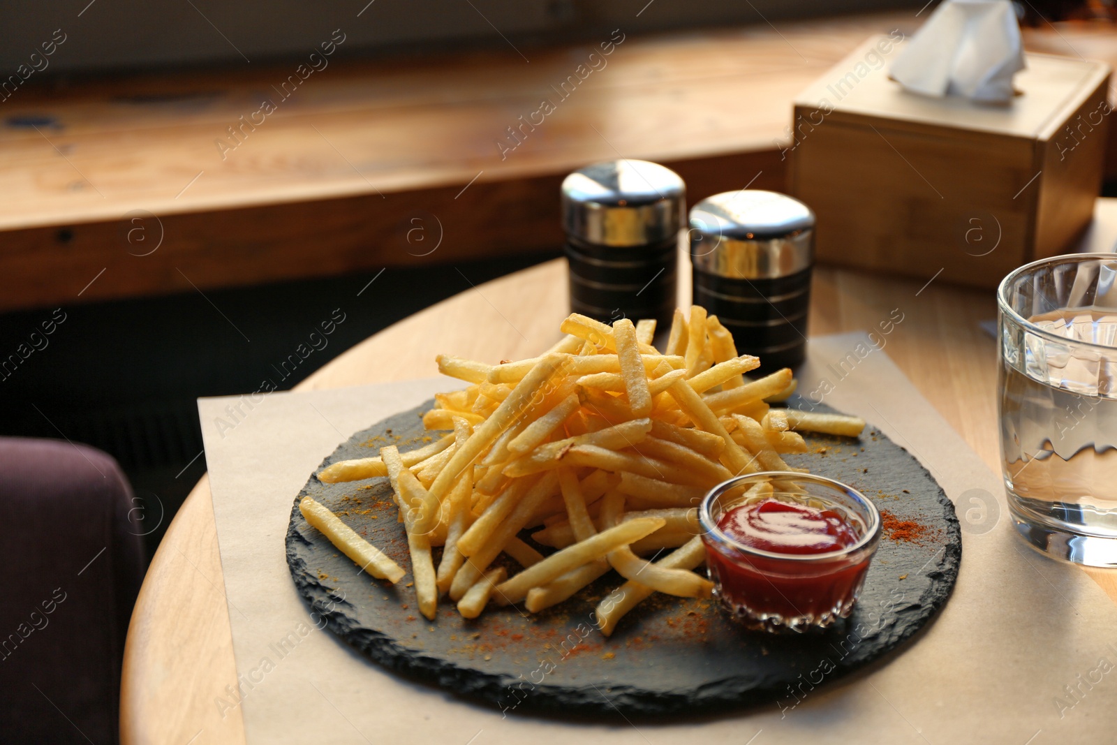 Photo of Tasty French fries with red sauce served on table in cafe