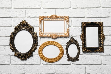 Photo of Blank vintage frames hanging on white brick wall. Mockup for design