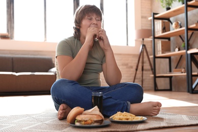 Overweight boy with fast food at home