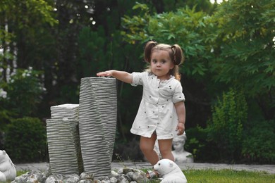 Photo of Cute little girl walking near decor elements in green park