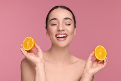 Photo of Beautiful young woman with pieces of orange on pink background