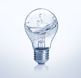 Image of Light bulb with water splashes on light background. Alternative energy source