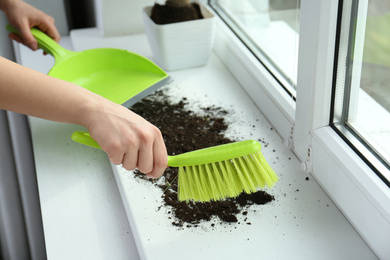 Woman cleaning window sill from soil at home, closeup