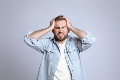 Photo of Young man suffering from headache on light background