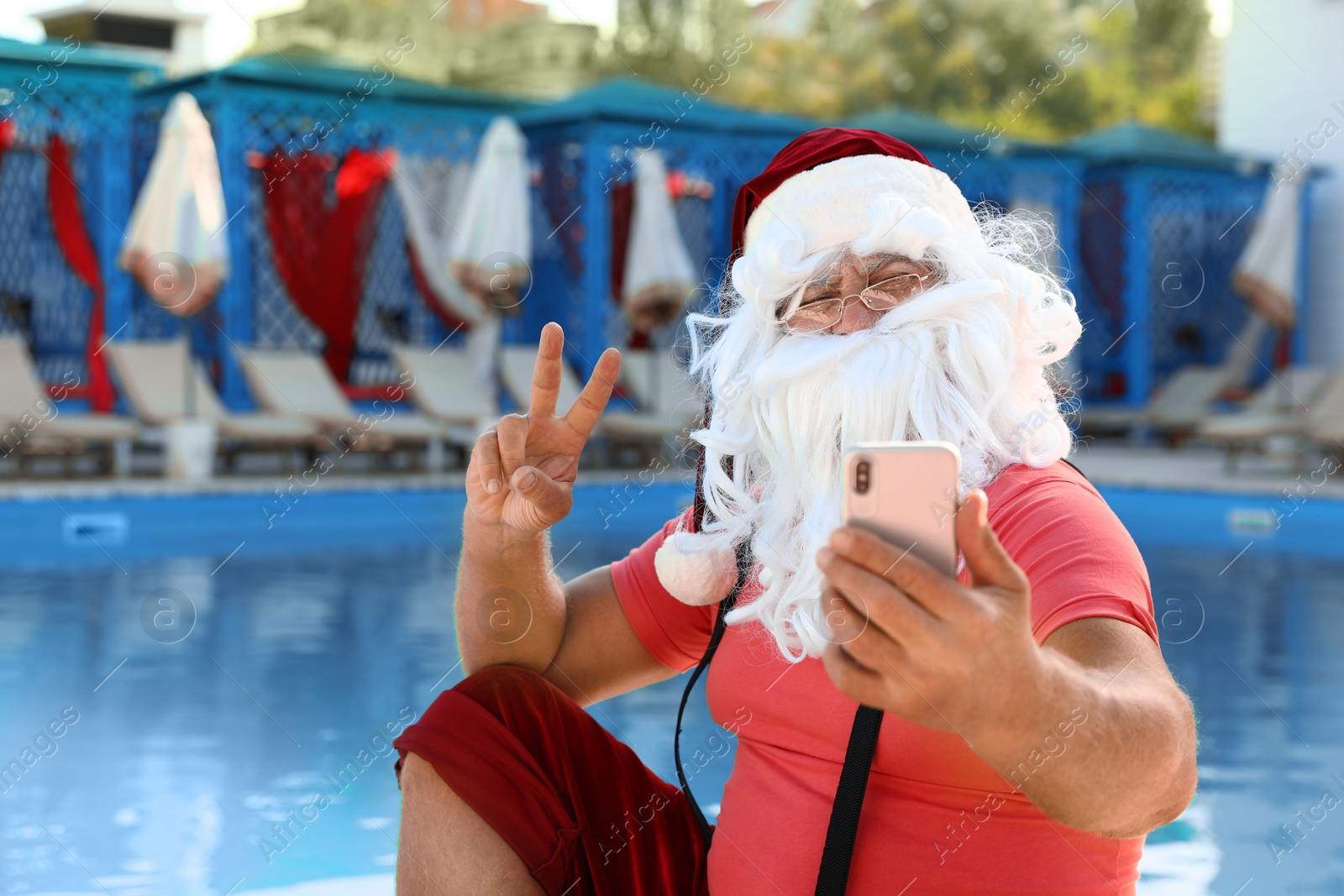 Photo of Authentic Santa Claus taking selfie near pool at resort