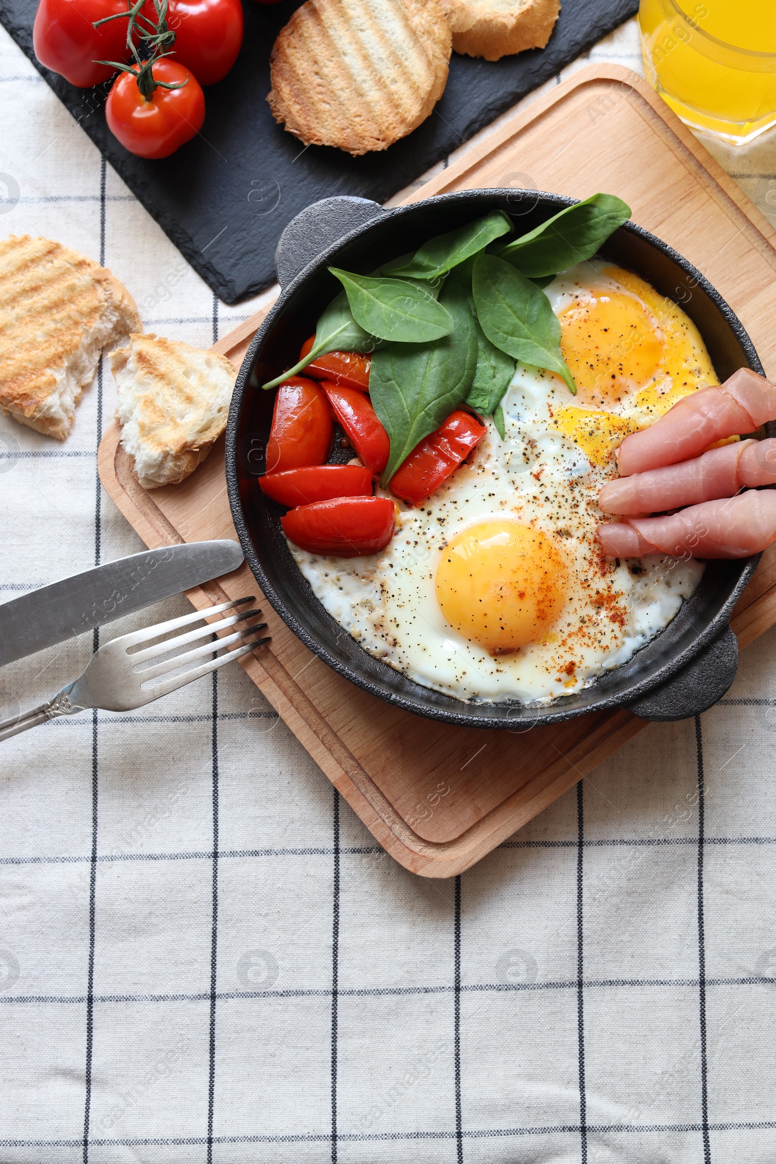 Photo of Delicious fried eggs with spinach, tomatoes and ham served on table, flat lay