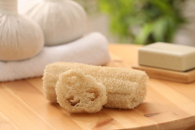 Photo of Loofah sponges on wooden table indoors, closeup