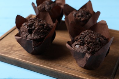 Tasty chocolate muffins on light blue table, closeup