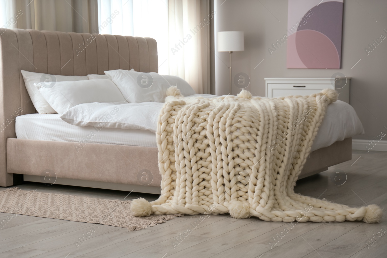 Photo of Soft knitted blanket on bed in room. Interior element