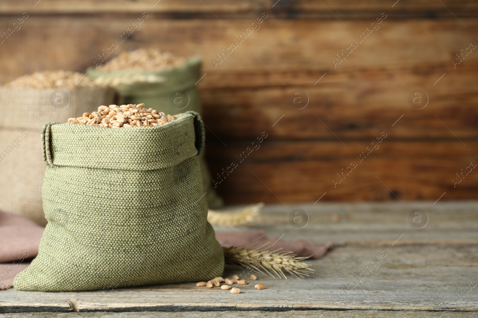 Photo of Sacks with wheat grains wooden wall, space for text