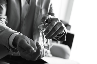 Photo of Man applying perfume on wrist indoors, closeup with space for text. Black and white effect