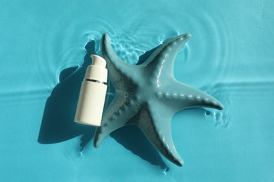 Moisturizing cream and sea star in water on light blue background, top view