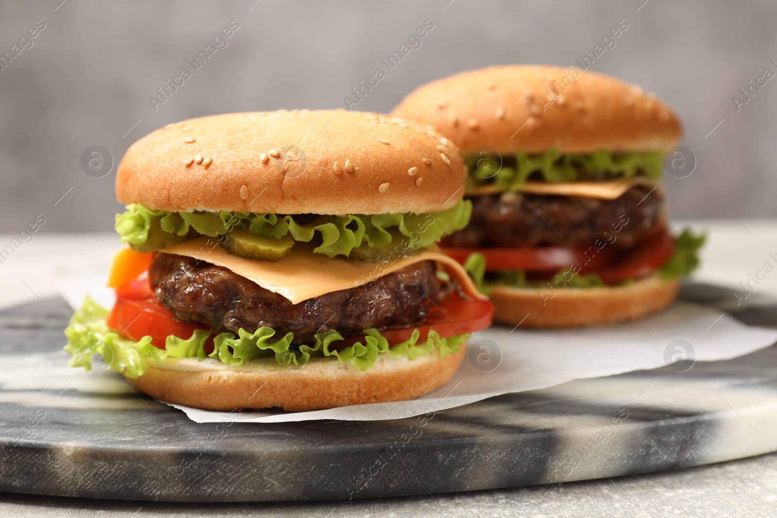 Photo of Tasty hamburgers with patties on light grey table, closeup