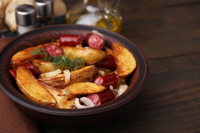 Photo of Delicious baked potato with thin dry smoked sausages, onion and dill in bowl on wooden table, closeup