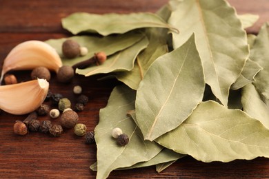 Aromatic bay leaves and spices on wooden table, closeup