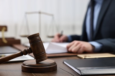 Lawyer working with documents at wooden table, focus on gavel