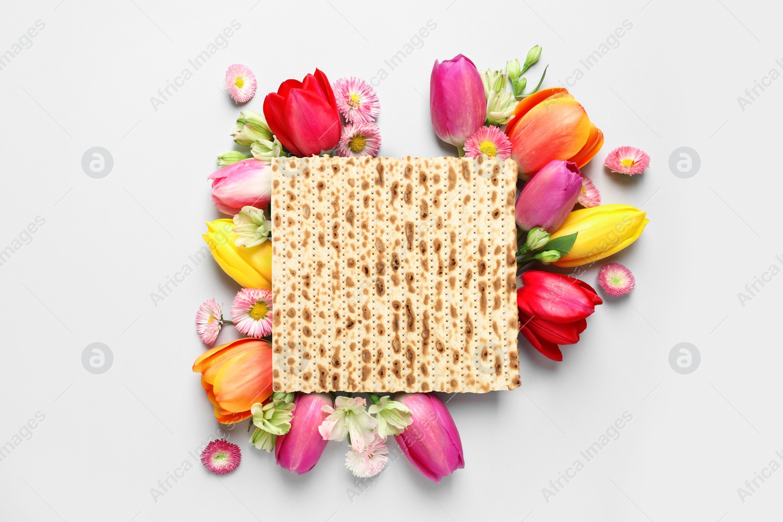 Image of Tasty matzo and flowers on light background, flat lay. Passover (Pesach) celebration