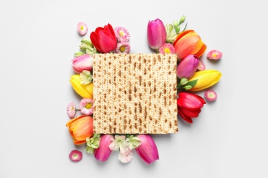 Image of Tasty matzo and flowers on light background, flat lay. Passover (Pesach) celebration