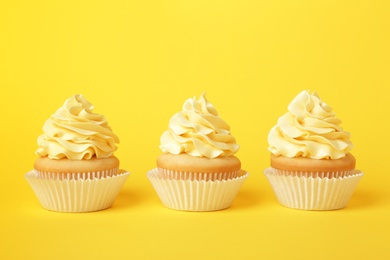 Photo of Tasty cupcakes with cream on yellow background