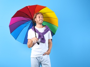 Photo of Man with rainbow umbrella on color background. Space for text