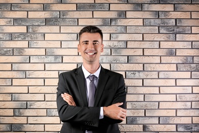 Handsome young man in suit near brick wall background