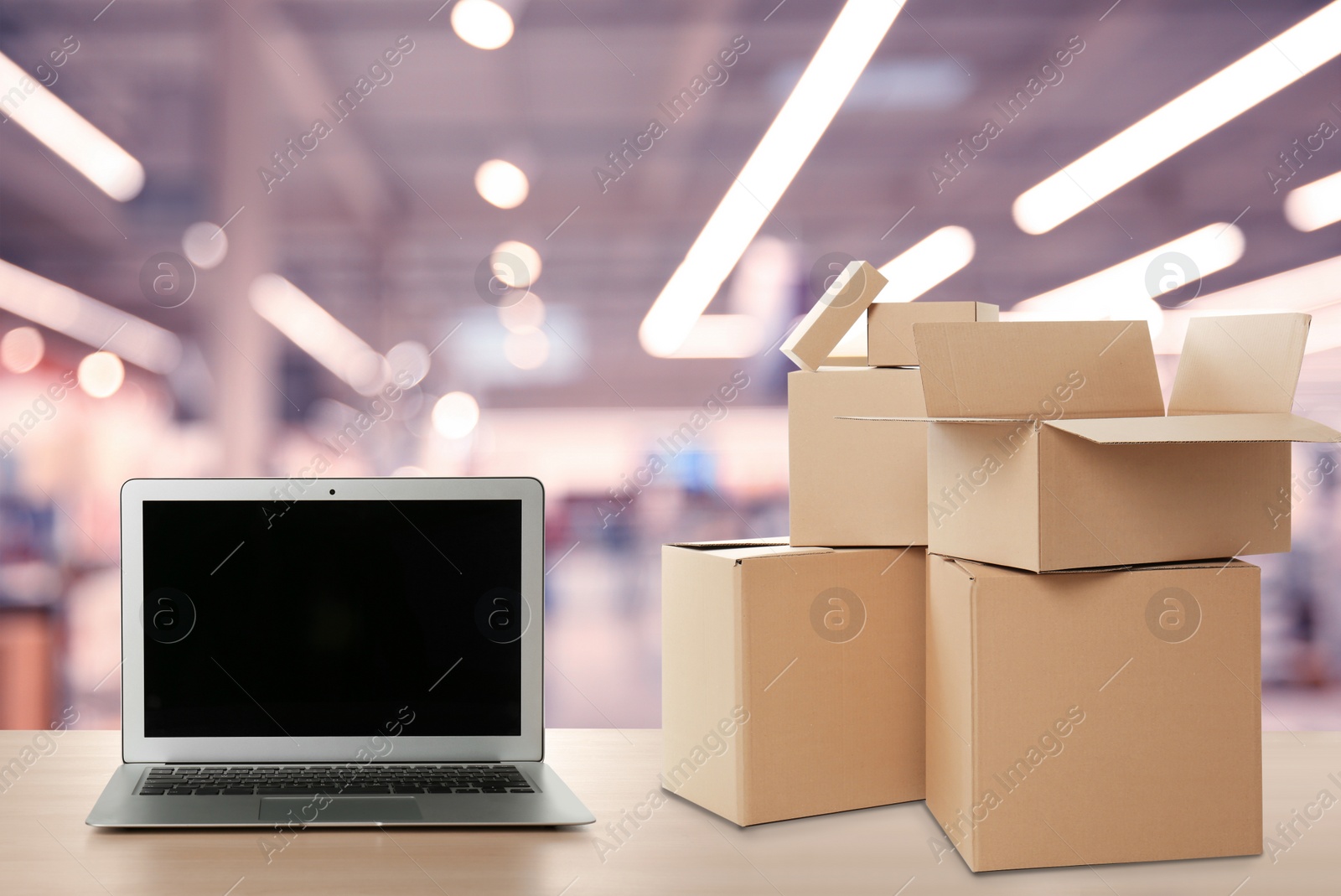 Image of Online selling. Laptop and parcels on table in store