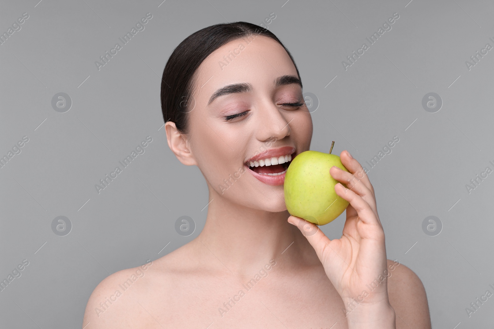 Photo of Beautiful young woman with apple on grey background