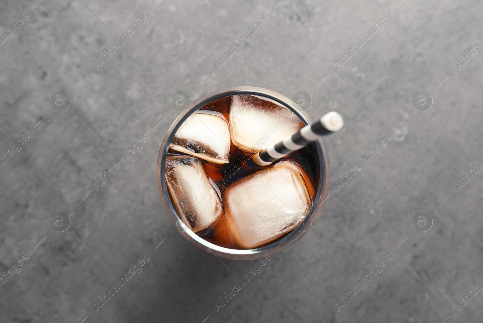 Photo of Glass of refreshing cola with ice on grey background, top view