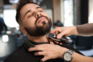 Professional hairdresser working with client in barbershop