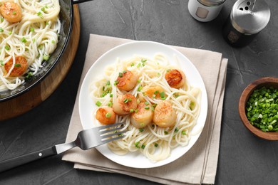Photo of Delicious scallop pasta with green onion served on grey table, flat lay