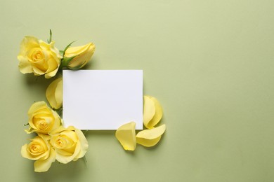 Photo of Beautiful yellow roses, petals and blank card on light olive background, flat lay. Space for text