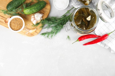 Flat lay composition with jar of pickled cucumbers on light table, space for text