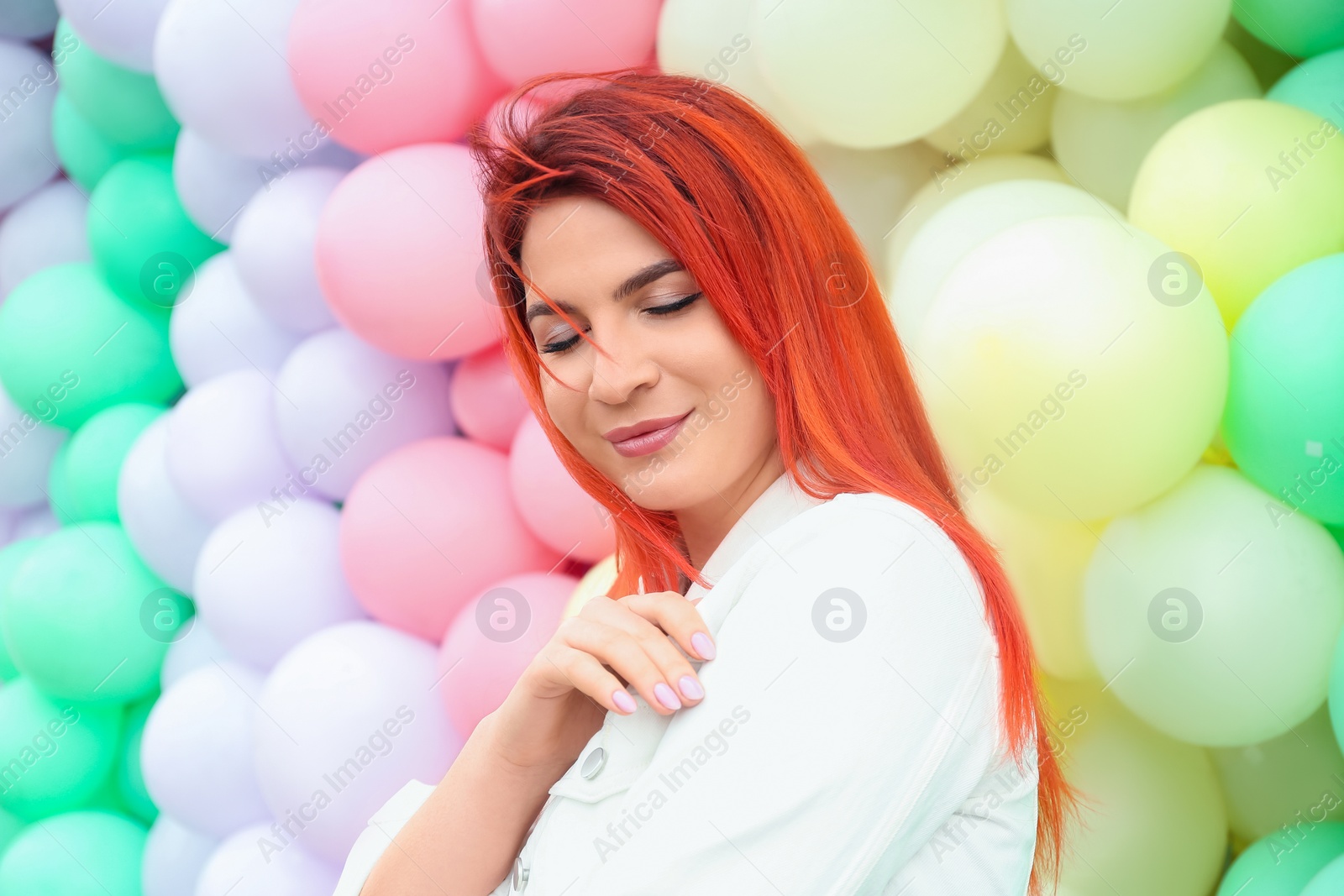 Photo of Young woman with bright dyed hair near colorful balloons