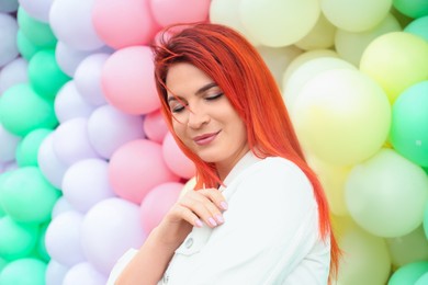Young woman with bright dyed hair near colorful balloons