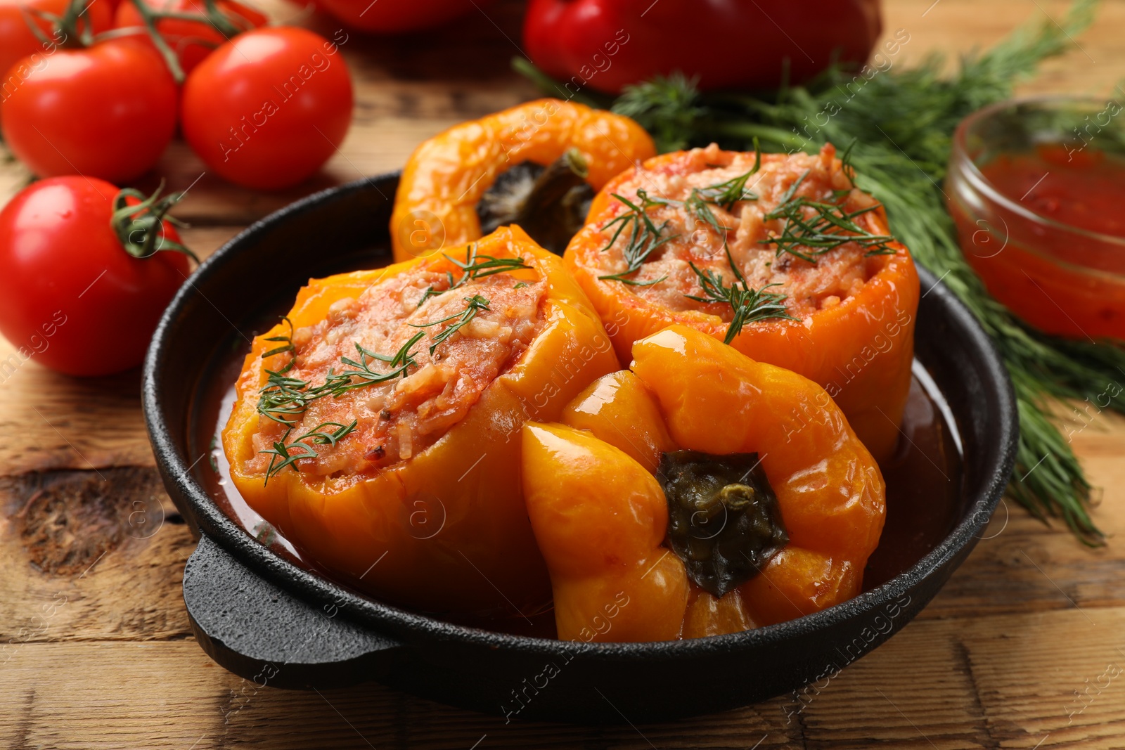 Photo of Tasty stuffed peppers in pan on wooden table, closeup