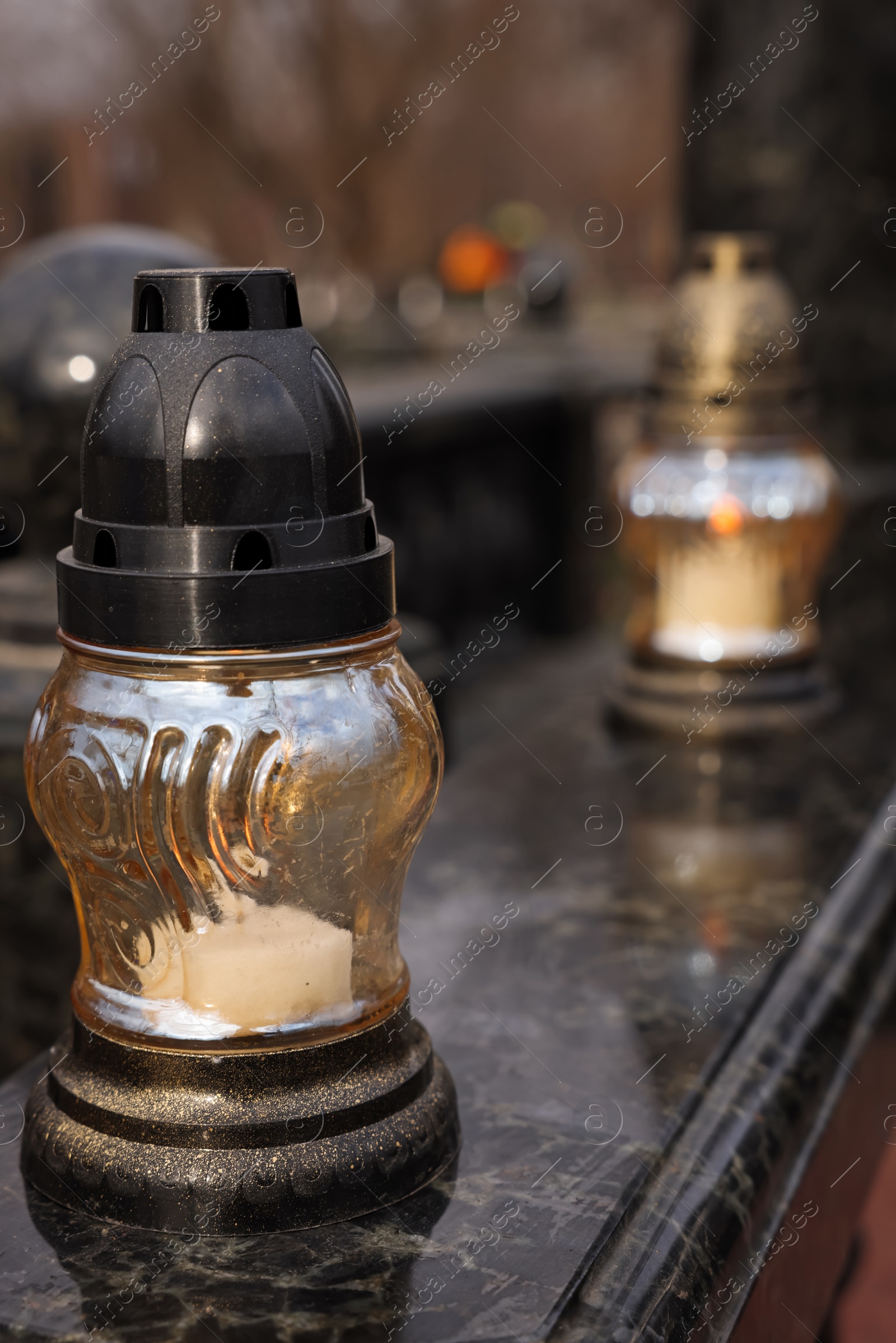 Photo of Grave lantern with candle on granite surface at cemetery