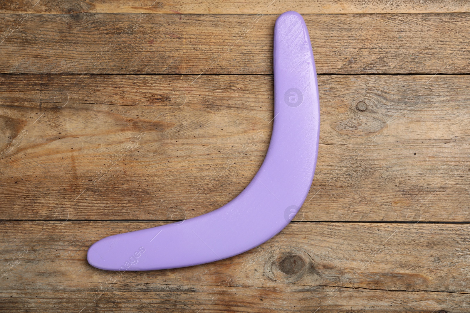 Photo of Purple boomerang on wooden background, top view