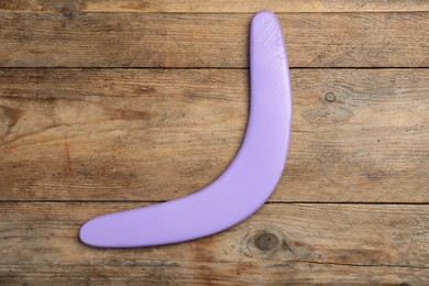 Photo of Purple boomerang on wooden background, top view