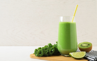 Photo of Tasty fresh kale smoothie on white wooden table. Space for text