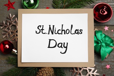 Card with phrase St Nicholas Day and festive decor on wooden table, flat lay