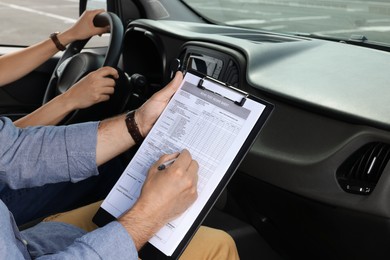 Photo of Driving school. Student passing driving test with examiner in car at parking lot, closeup