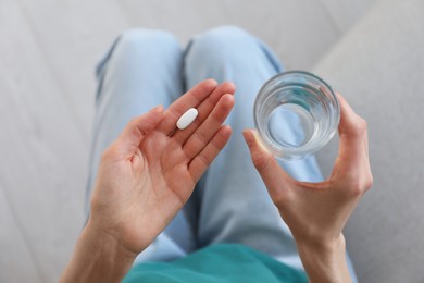 Photo of Young woman with abortion pill and glass of water, top view