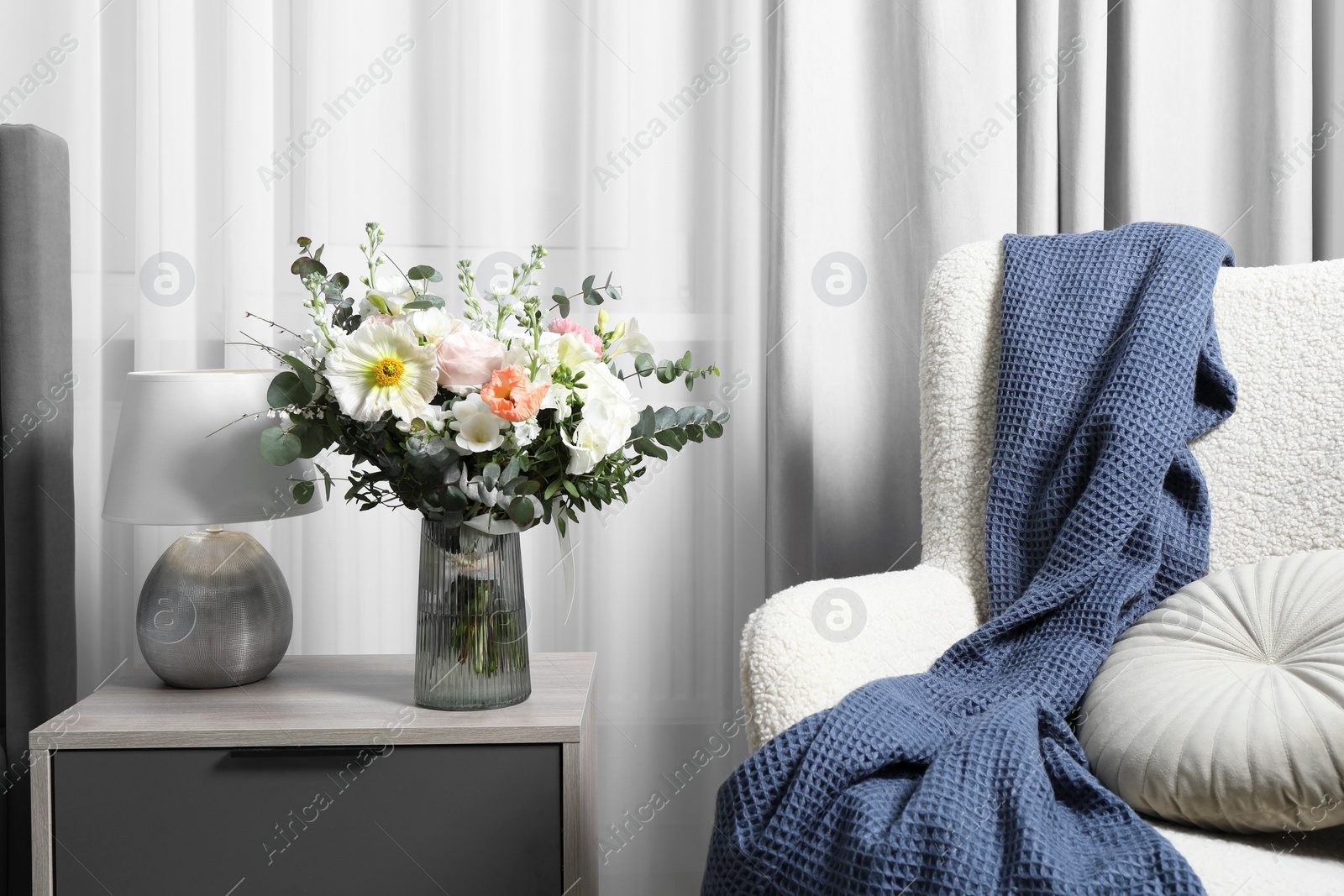 Photo of Bouquet of beautiful flowers near armchair indoors