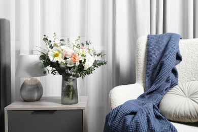 Photo of Bouquet of beautiful flowers near armchair indoors